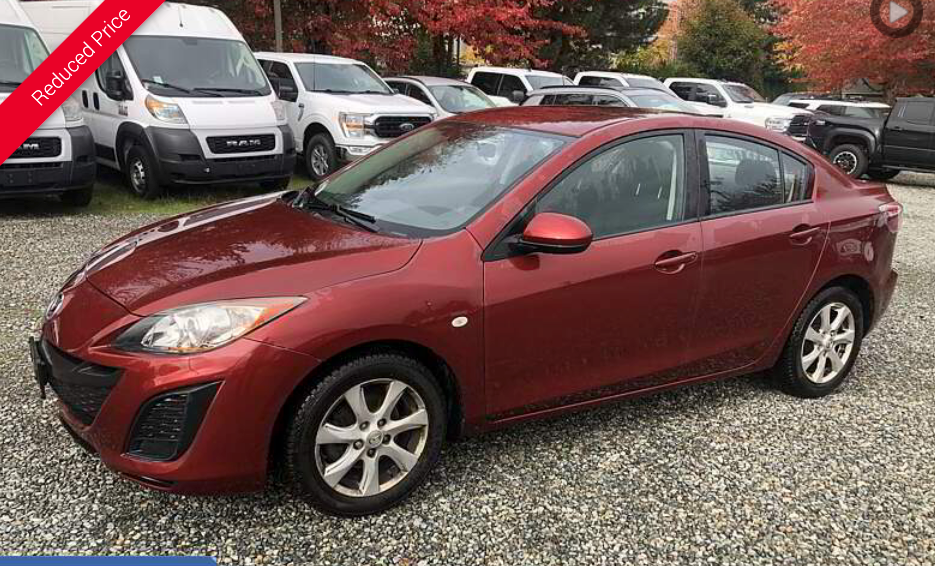 Red Mazda 3 sedan parked outdoors at a dealership.