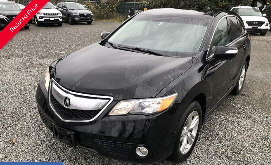 Black Acura RDX SUV parked outdoors on gravel, viewed from the front.