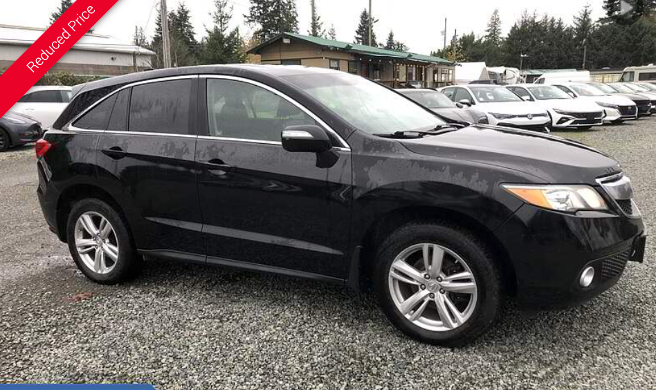 Black Acura RDX SUV parked on gravel at a car dealership on an overcast day.