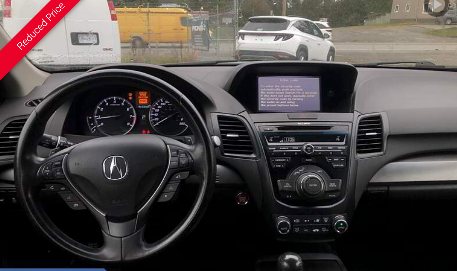 Dashboard of an Acura RDX, black with steering wheel, gauges, and infotainment screen.