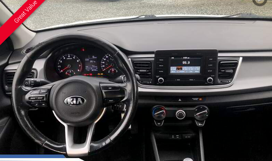 Dashboard of a Kia Rio, featuring steering wheel, infotainment screen, and climate controls.