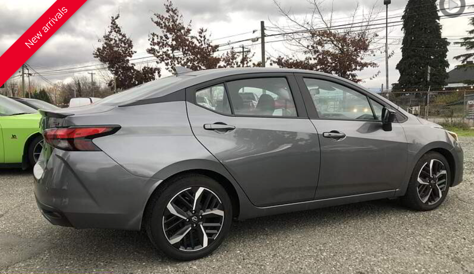Gray Nissan sedan parked outdoors, side view.