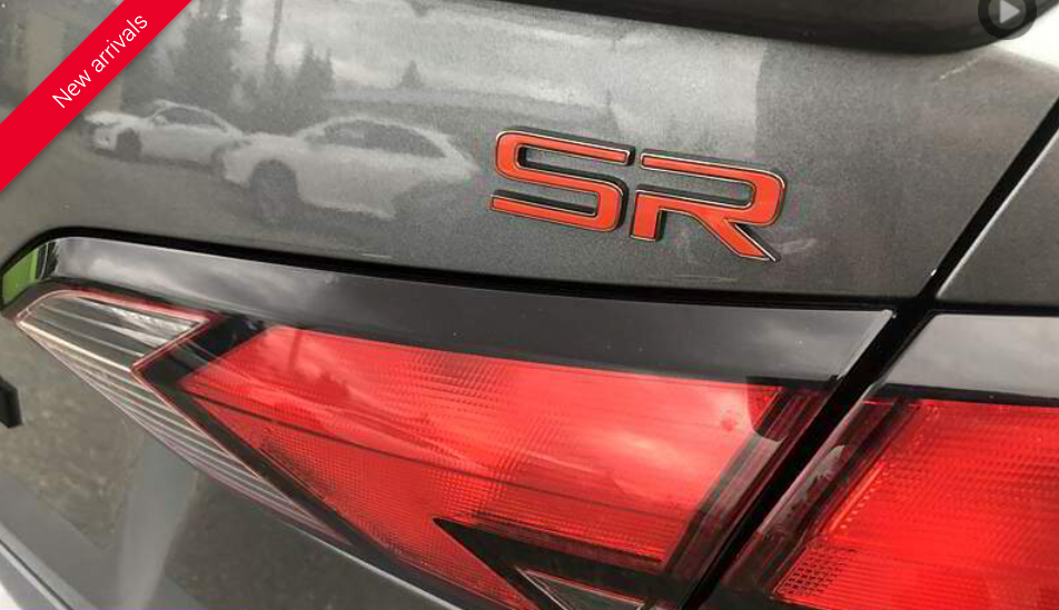 Gray car trunk with orange SR emblem and red taillight.