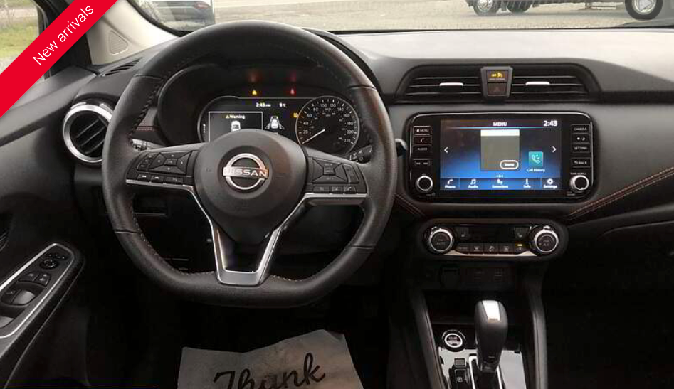 Dashboard of a Nissan with a black steering wheel, infotainment screen, and controls.