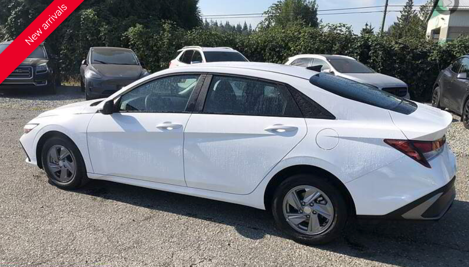 White sedan parked outside, other cars in background.