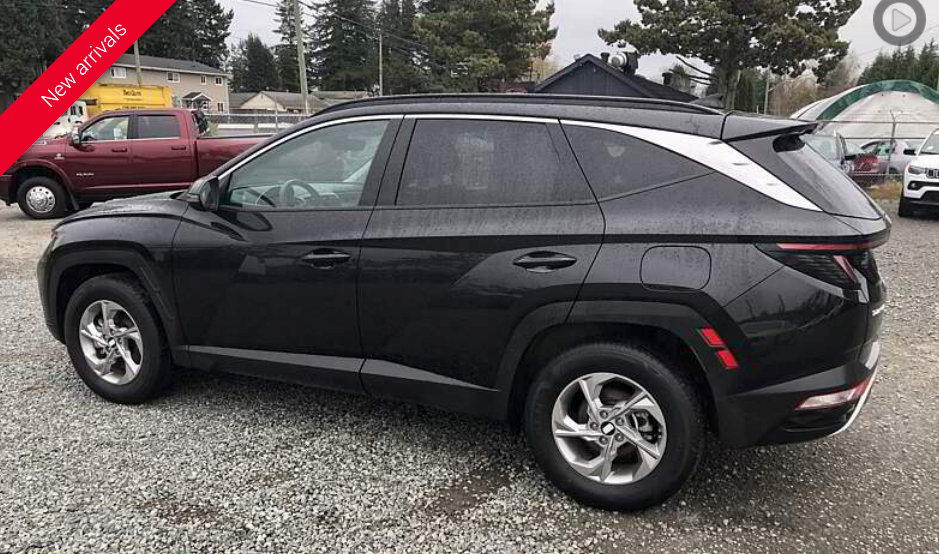 Black Hyundai Tucson SUV parked outdoors on a cloudy day.