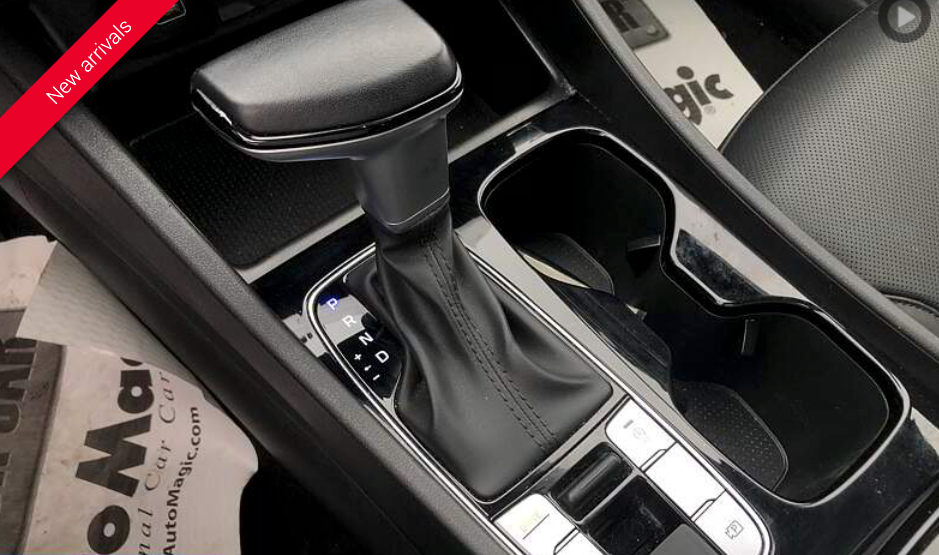 Car's center console with gear shift lever, cup holder, and various buttons.
