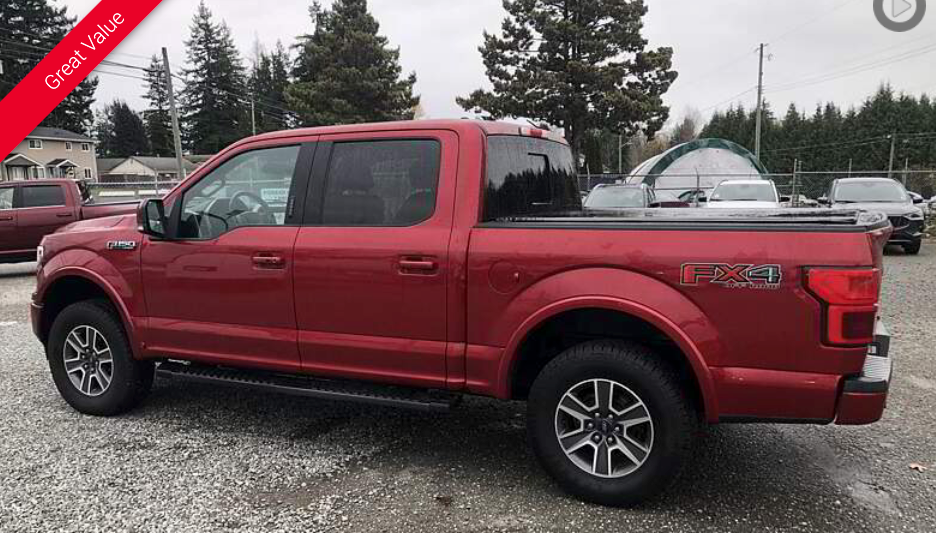 Red Ford F-150 pickup truck with black trim, parked outside on a cloudy day.