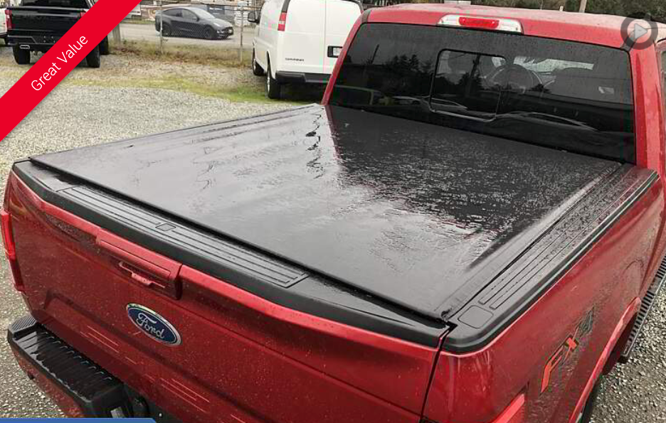 Red pickup truck with a black tonneau cover; parked outside.