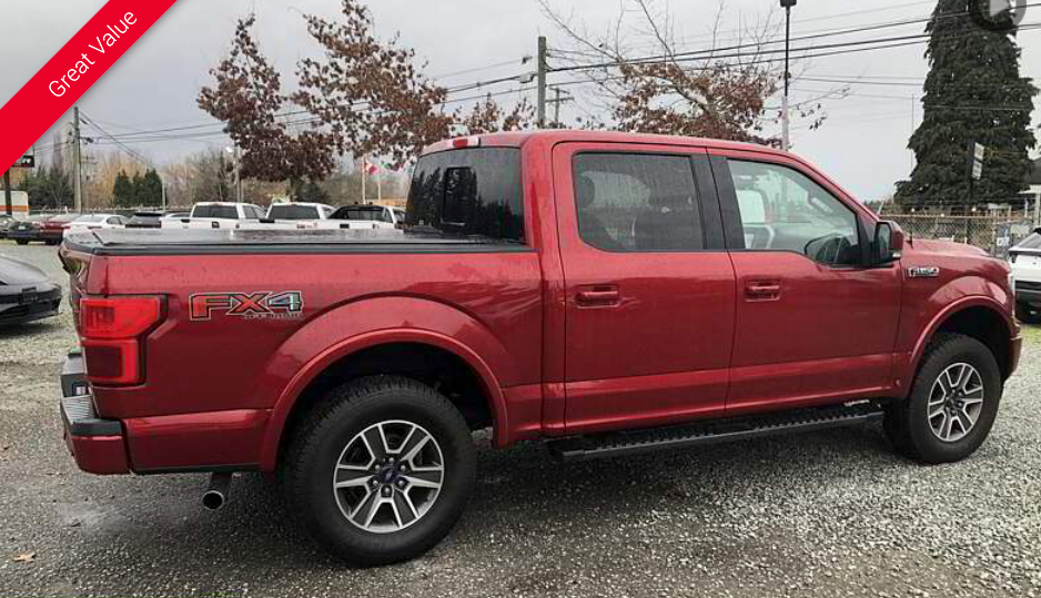 Red Ford F-150 pickup truck with black bed cover, parked outside on a cloudy day.