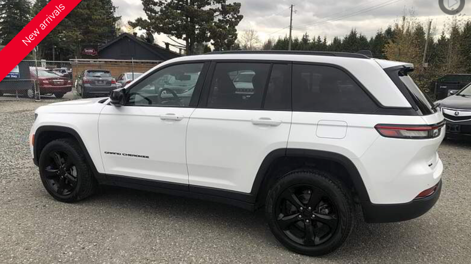White Jeep Grand Cherokee SUV with black wheels parked outside.