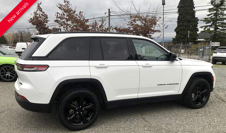 White Jeep SUV with black wheels in a parking lot.