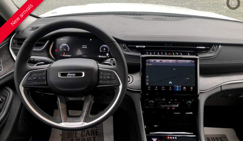 Dashboard of a white Jeep Grand Cherokee, featuring a large touchscreen and digital instrument panel.