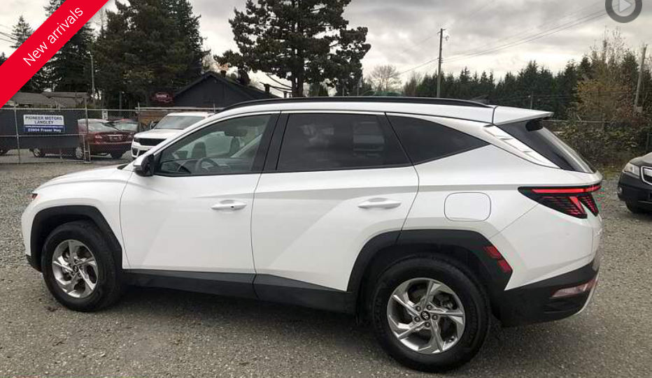 White Hyundai Tucson SUV parked outdoors on a gravel lot.