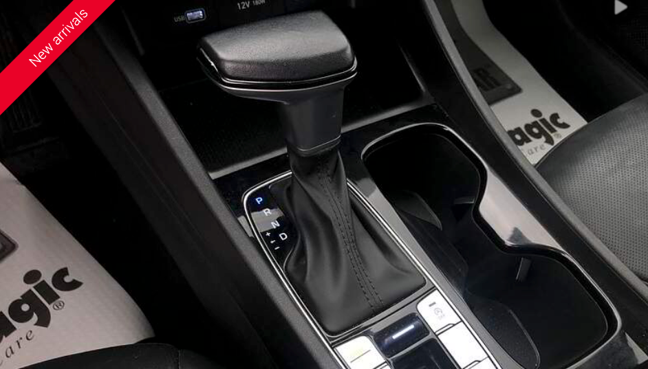 Interior car console with gear shift, cup holder, and various buttons.