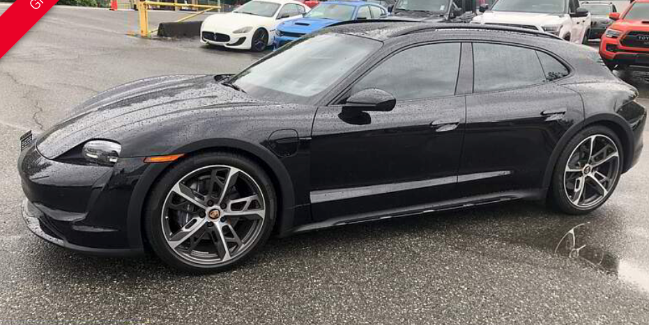 Black Porsche Taycan Cross Turismo parked on wet pavement.