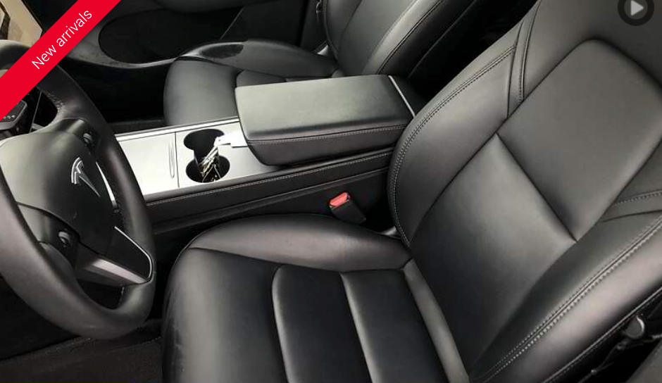 Black leather interior of a Tesla car, including seats, steering wheel, and center console with cup holders.