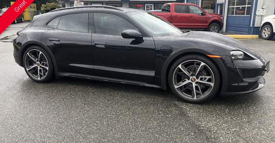 Black Porsche Taycan station wagon parked on a wet street.