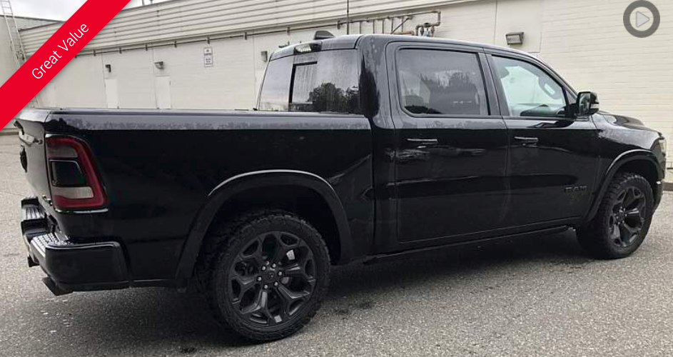 Black RAM pickup truck, parked, side view. Black wheels and trim. Outdoors.
