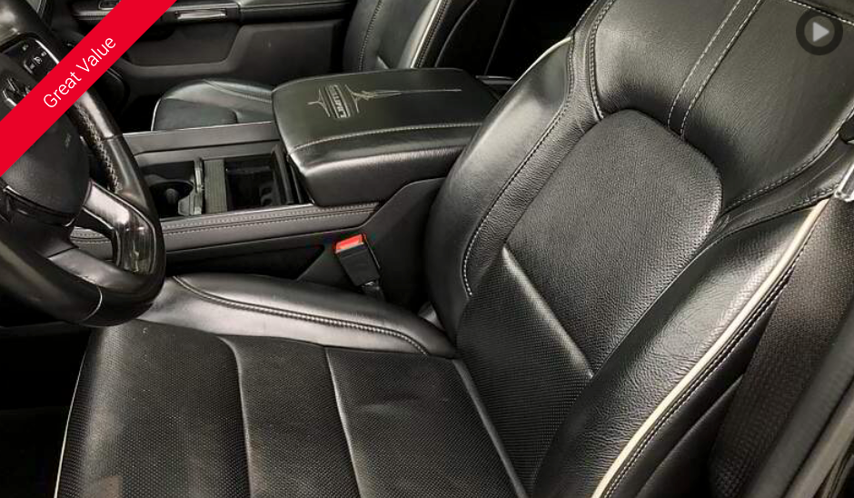 Black leather truck interior with white stitching, center console, and seat belt.
