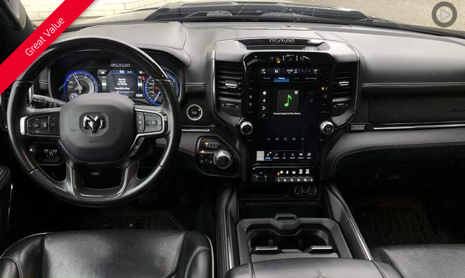 Dashboard of a black Ram truck with a large touchscreen display and steering wheel.