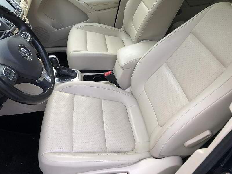 Cream-colored car interior. Front seats with perforated leather, steering wheel, and console visible.
