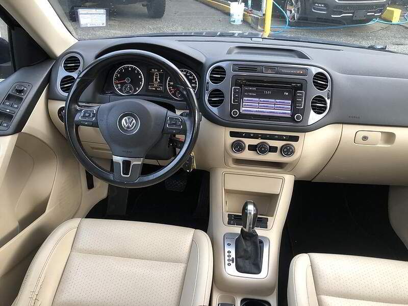 Interior of a tan Volkswagen Tiguan. Steering wheel, dashboard, and seats are visible.