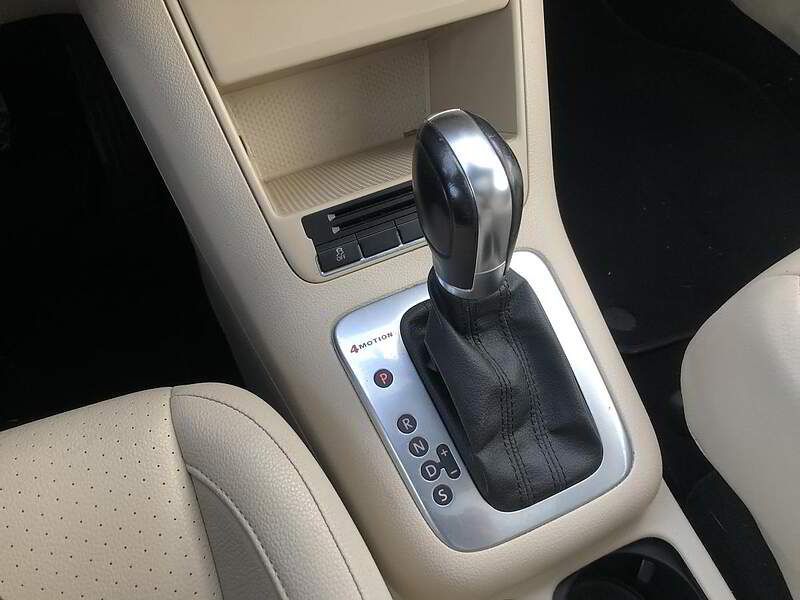 Car's center console with automatic gear shift, metallic, beige and black interior.
