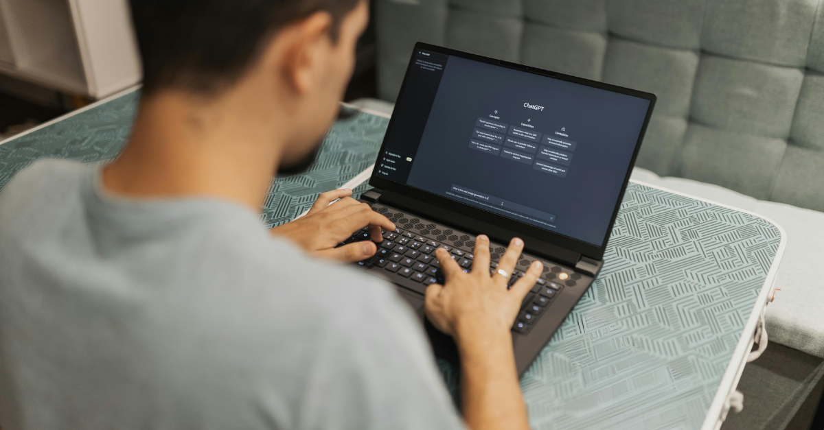 Person typing on a laptop with a software interface. Dark screen, hands on keyboard, inside setting.