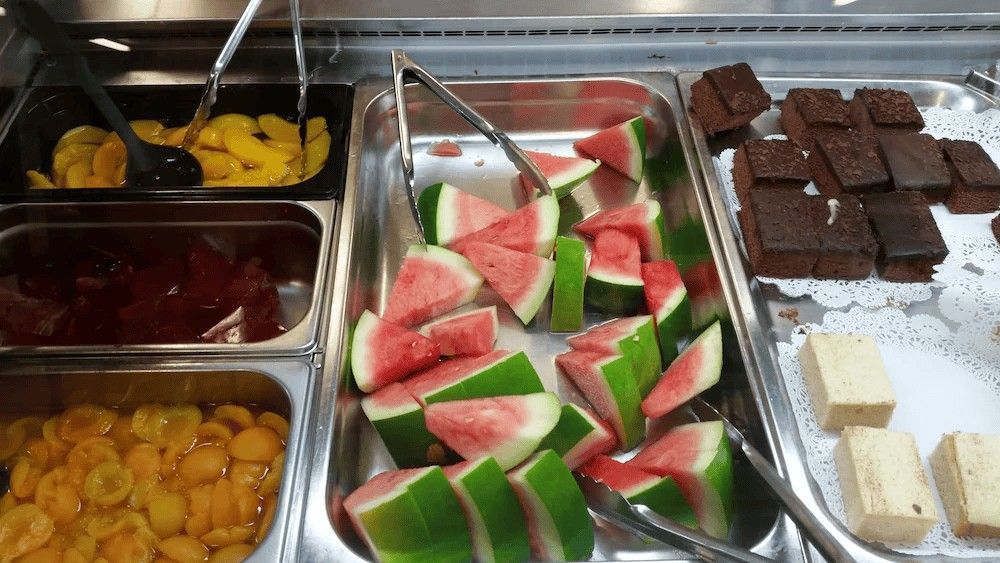 A Buffet with Watermelon, Apricots, Brownies, and Peaches in Metal Trays — Leichhardt Accommodation in Mornington, QLD
