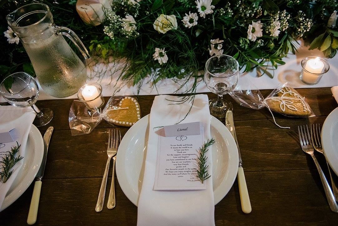 A table set for a wedding reception with plates , silverware , candles and flowers.