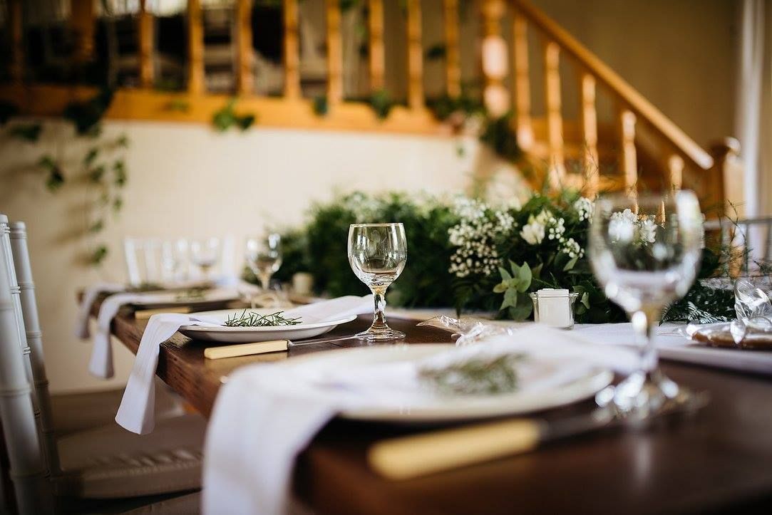 A table set for a wedding reception with plates and wine glasses.