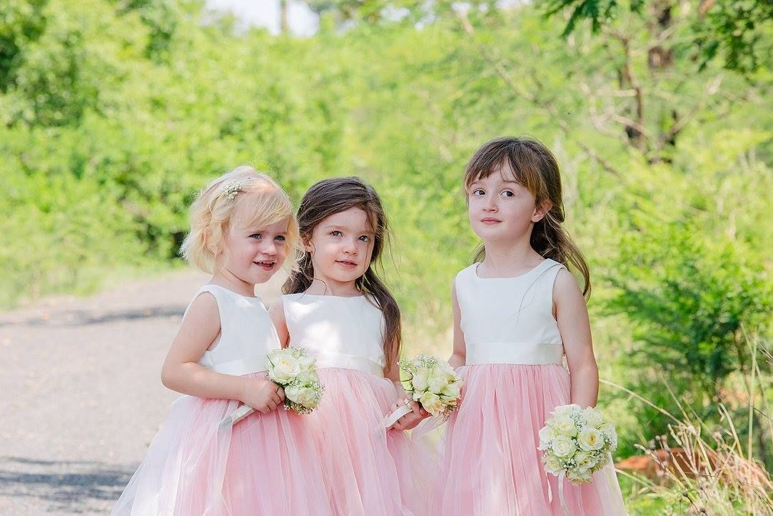 Three flower girls are standing next to each other holding bouquets of flowers.
