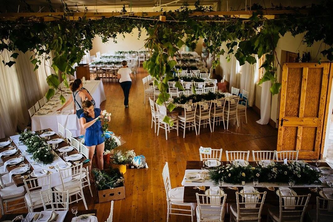 A large room filled with tables and chairs decorated for a wedding reception.
