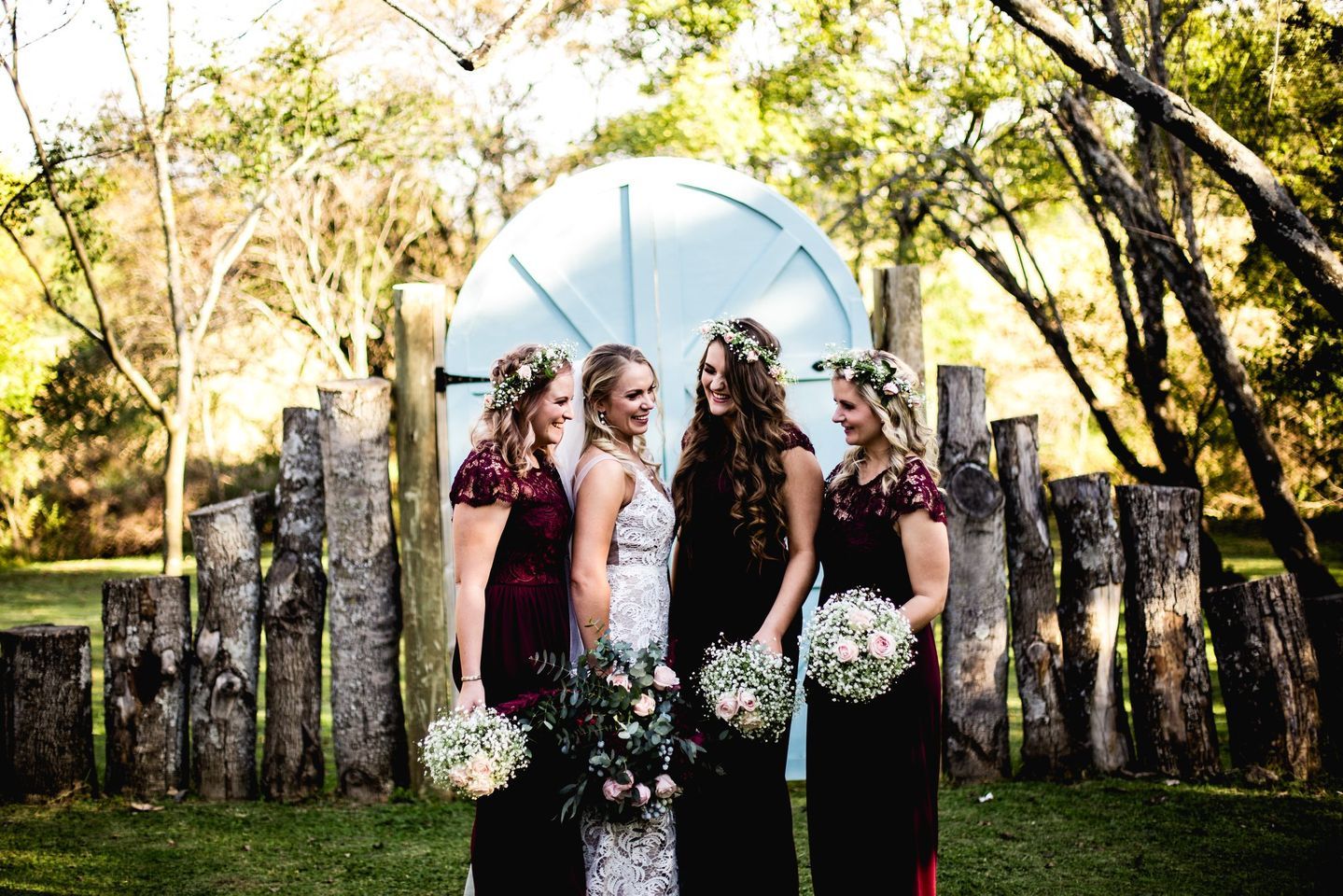 A bride and her bridesmaids are posing for a picture in front of a wooden archway.