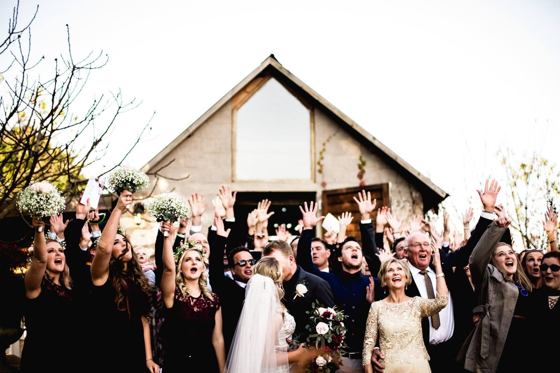 A group of people are standing in front of a church with their hands in the air.
