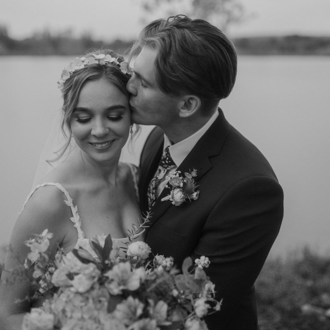 A bride and groom are kissing in a black and white photo.