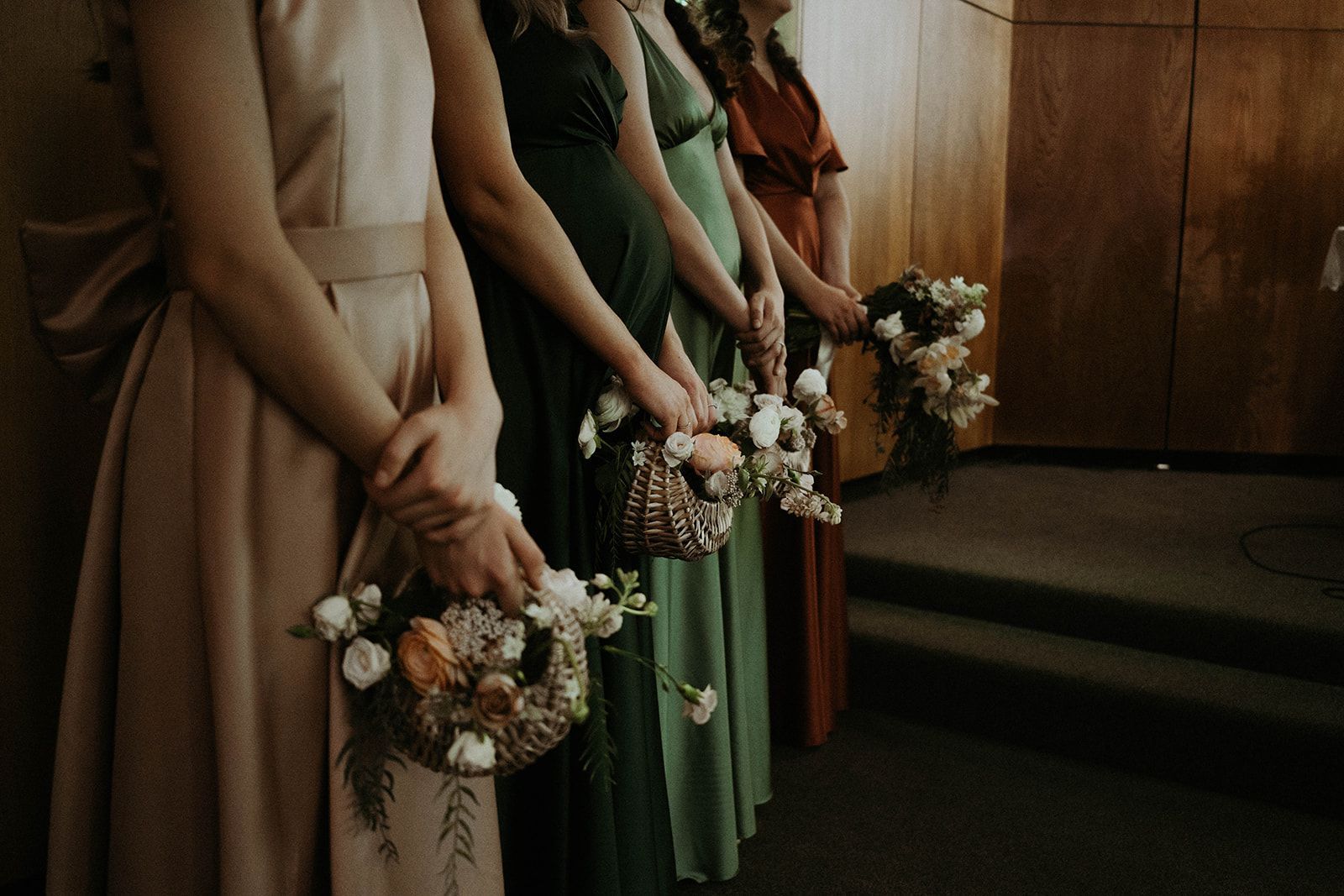 A group of bridesmaids standing next to each other holding baskets of flowers.
