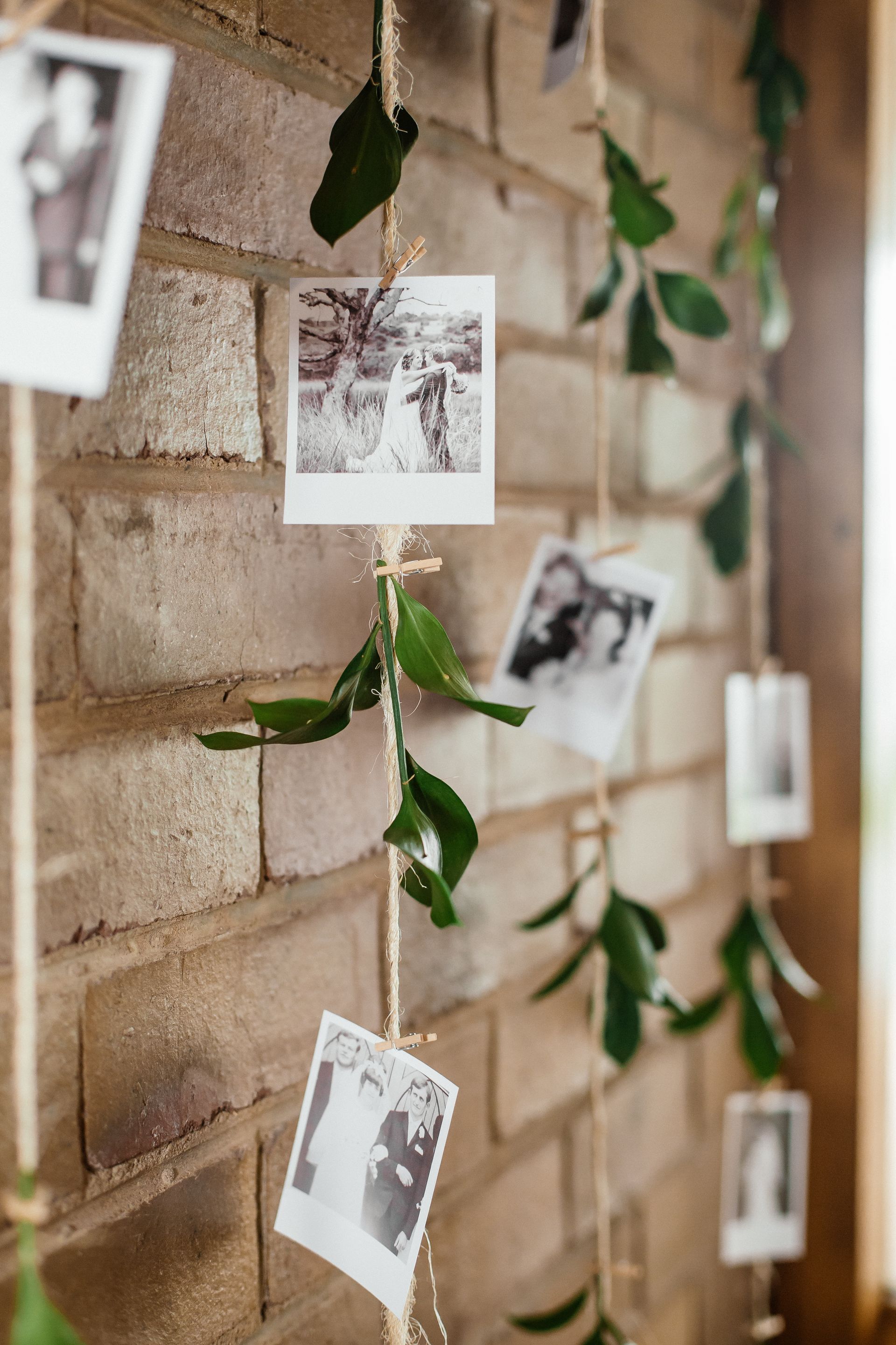 A string of polaroid pictures hanging on a brick wall.