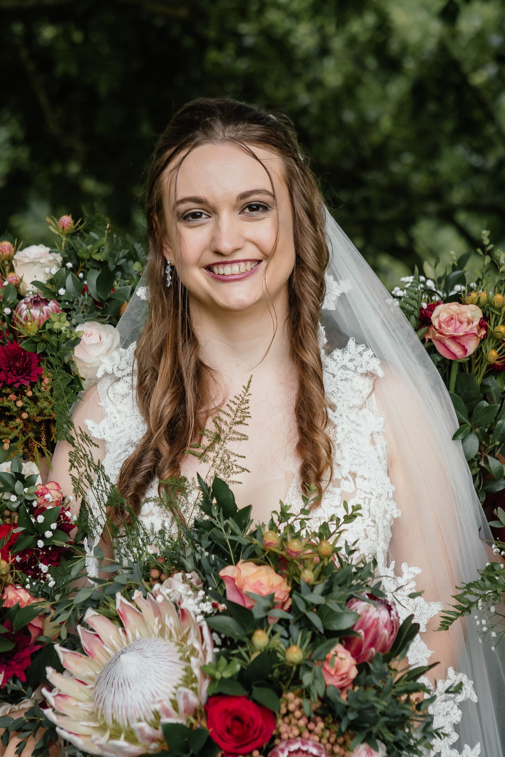 The bride is wearing a veil and holding a bouquet of flowers.