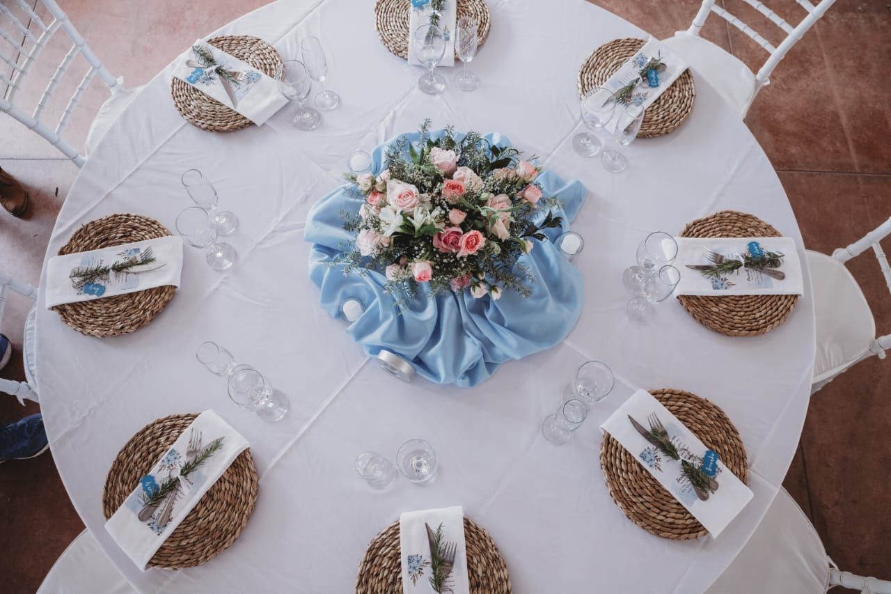 A table with plates , napkins , glasses and a vase of flowers on it.