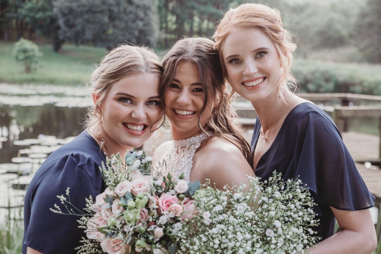A bride and her bridesmaids are posing for a picture while holding bouquets of flowers.
