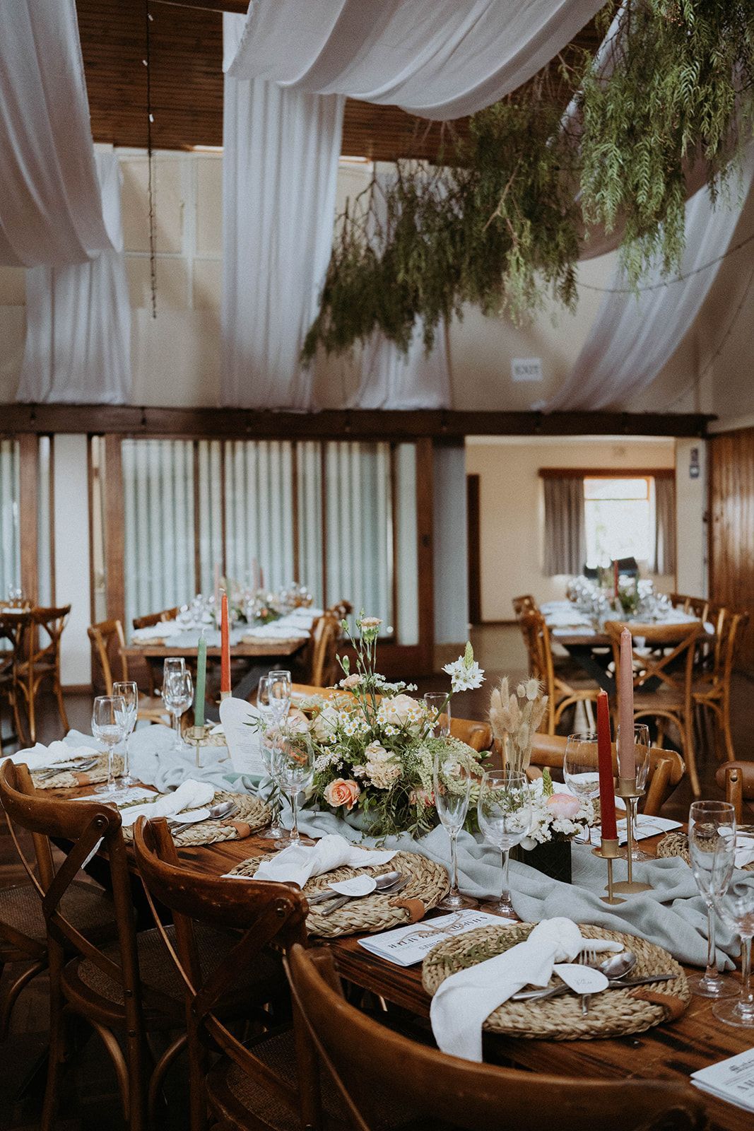 A long table set for a wedding reception with candles and flowers on it.