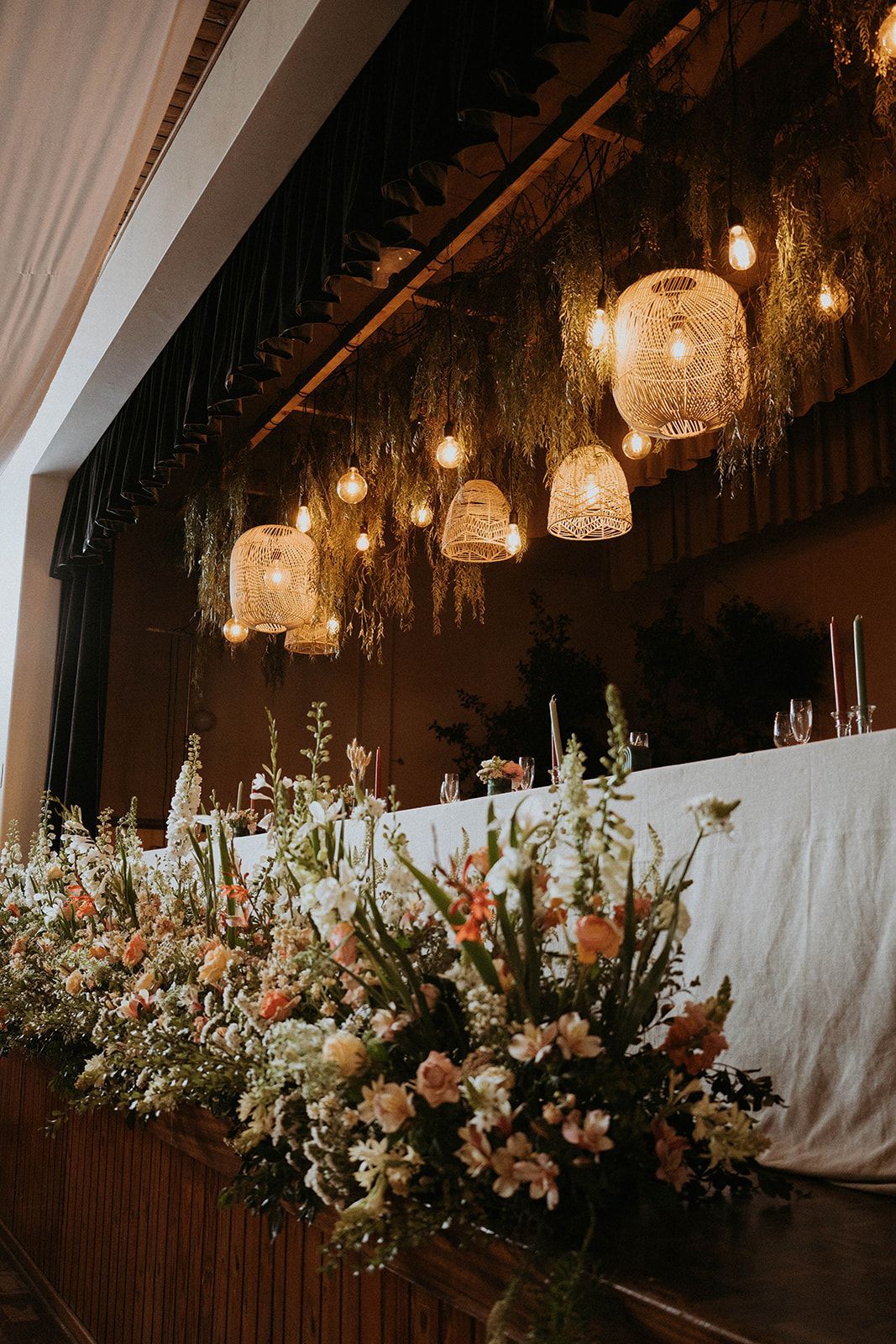 A long table with flowers and lights hanging from the ceiling.