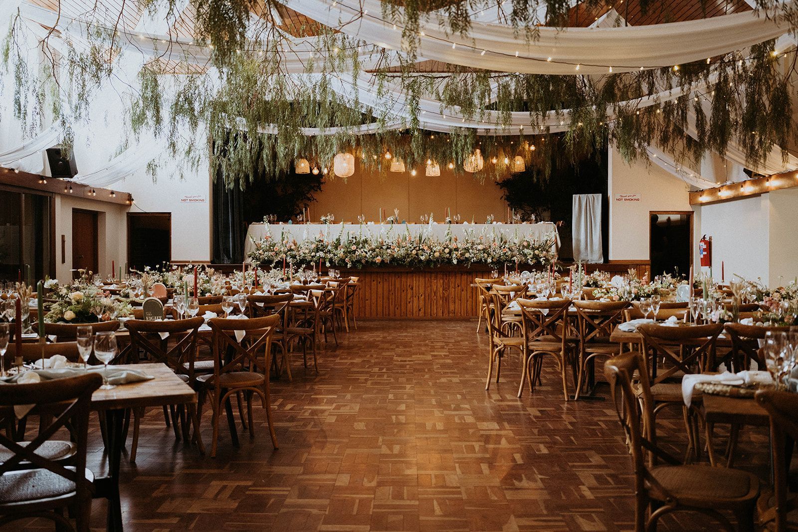 A large room with tables and chairs set up for a wedding reception.