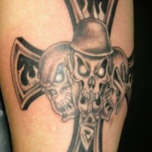 A tattoo of a cross with three skulls on it