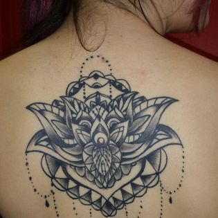 A woman has a tattoo of a lotus flower on her back.
