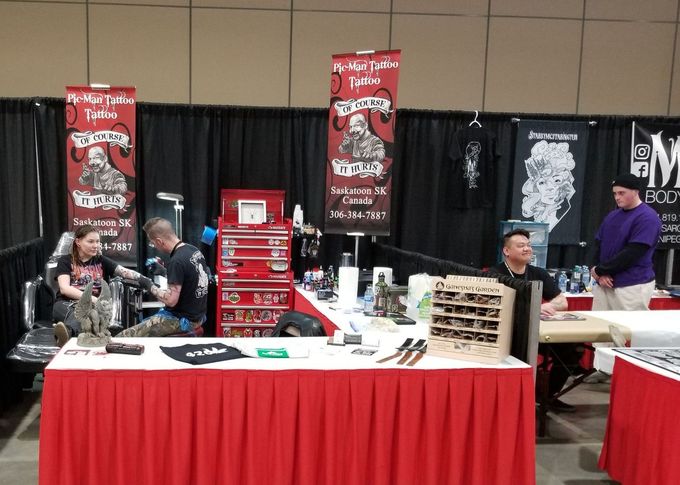 A group of people are standing around a table at a convention.