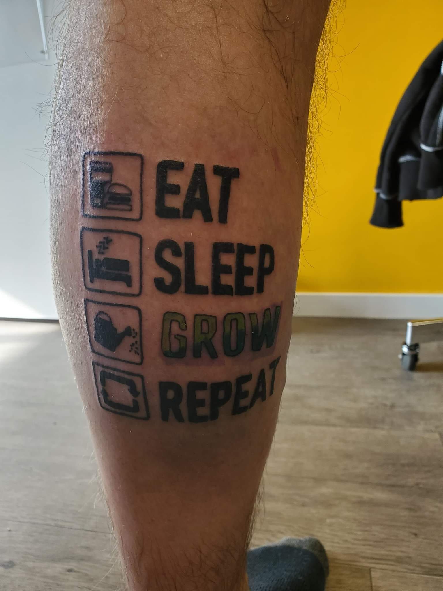 A man has a tattoo on his leg that says eat sleep grow repeat