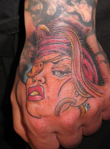 A man has a tattoo of a woman 's face on his hand.